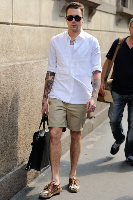 a white shirt with pockets, a white top under it, tan shorts, printed shoes and a black bag