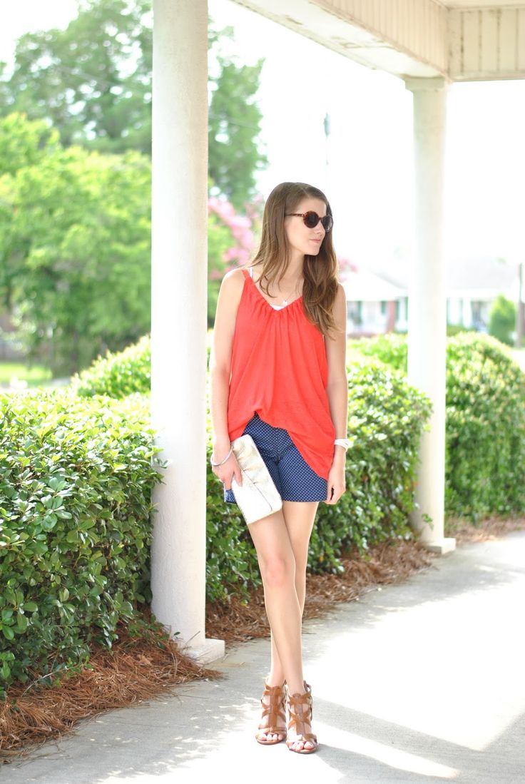 blue patterned shorts, a red top and a white clutch