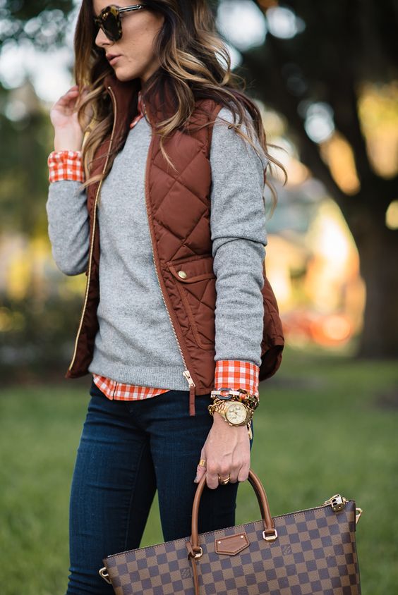a grey jersey, a plaid shirt, a puffed vest and jeans