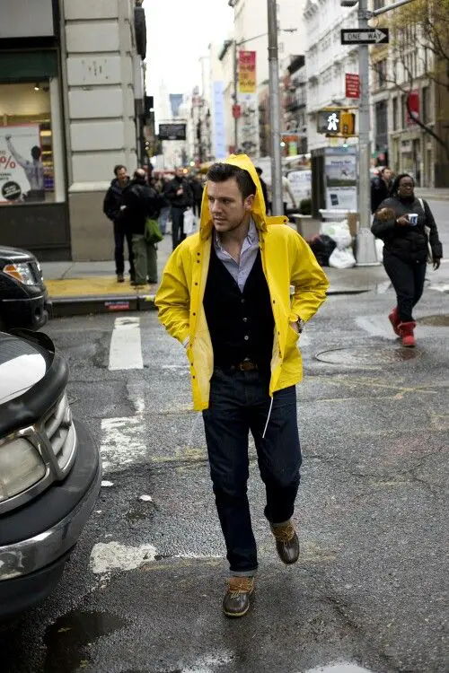 navy jeans, a black cardigan and a yellow rain coat
