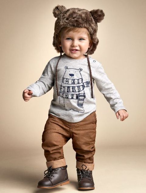 brown pants, a grey printed long sleeve, brown boots and a fur hat