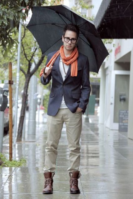 perfect early fall outfit with grey pants, a navy jacket, brown boots and an orange scarf