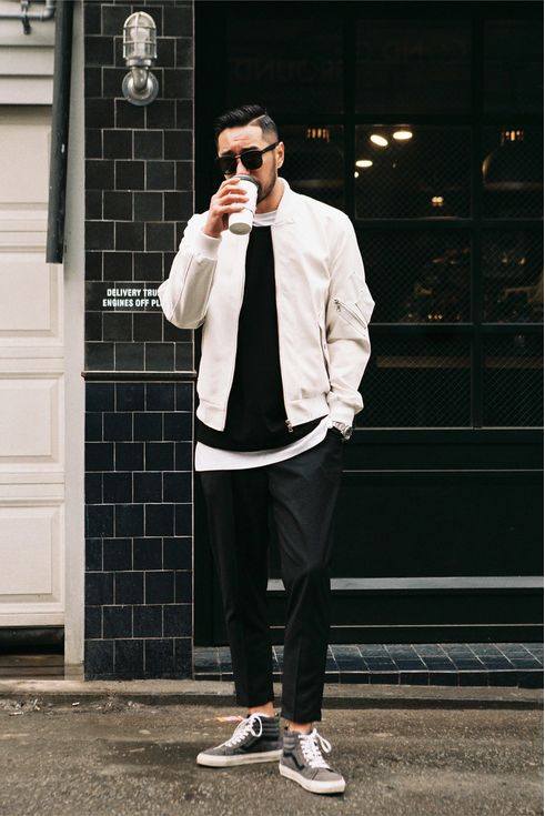 layered look with black pants, a white bomber jacket,a black sweater and grey chucks
