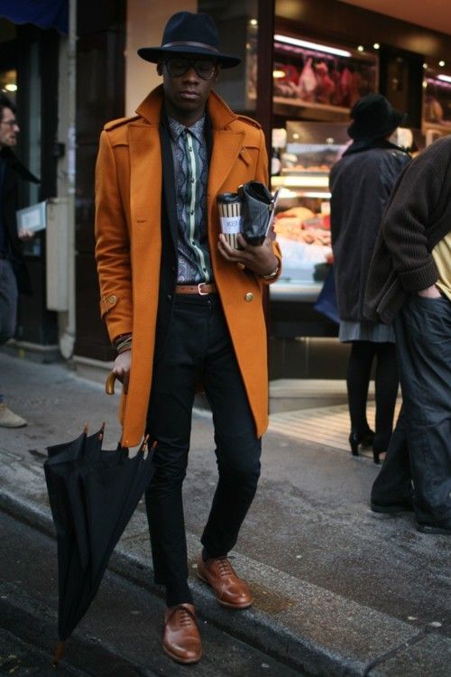 ocher coat, black pants, a printed shirt and brown boots