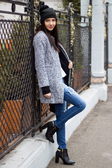 With distressed jeans, black ankle boots and hat