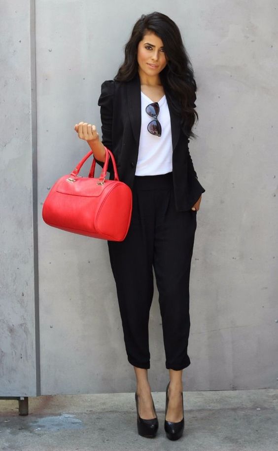 black pant suit, a white top, heels and a red bag