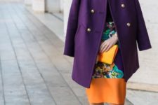 With black shirt, colorful printed knee-length skirt and clutch