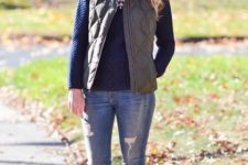 With distressed jeans, sweater and puffer vest