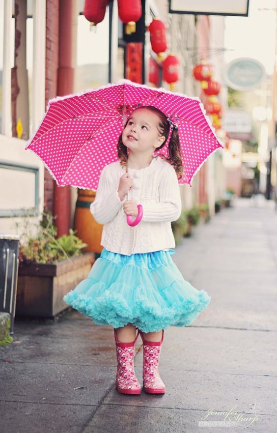 pink printed rain boots, a ruffled blue skirt and a white cardigan