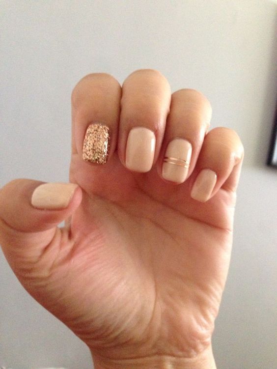 neutral nails with a gold glitter accne tone and gold stripes