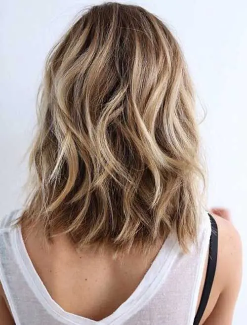 a long wavy bob with shades of blonde and light brown for a natural look and a bleached beach inspired touch