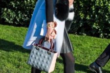 With black shirt, printed skirt, long vest with fur and small bag