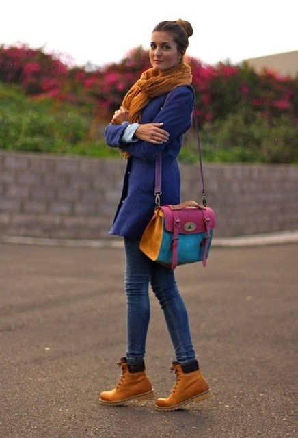 With blue coat, orange scarf, jeans and colorful bag