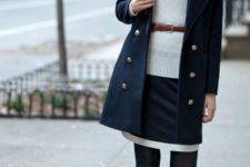 With double breasted navy blue coat, brown ankle boots and leather belt