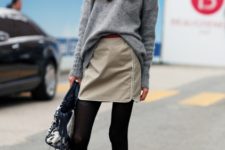 With gray sweater, mini skirt, black tights and leather bag