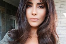 a beautiful dark brunette medium-length haircut with short curtain bangs and waves and some volume looks cool