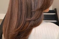 a beautiful long chestnut butterfly haircut with a lot of volume and curled ends is a stylish and catchy idea