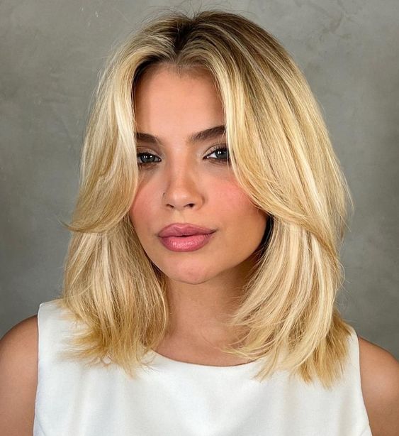 a bright blonde long bob with side bangs and a darker root is a chic and catchy idea to make a statement
