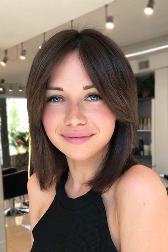 a long bob haircut in brown with side bangs and a middle part is a good idea for both straight and wavy hair