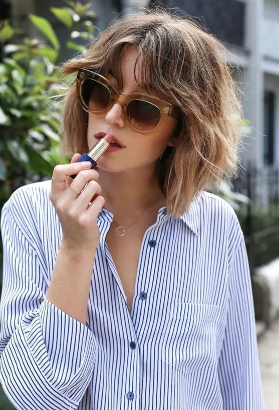 a lovely light brunette shaggy long bob with caramel balayage and a lot of texture plus curtain bangs is cool