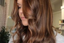 medium-length chestnut hair with golden blonde balayage, waves and volume, is a catchy and chic idea