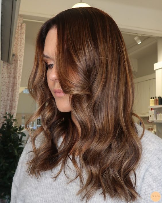 Medium length chestnut hair with golden blonde balayage, waves and volume, is a catchy and chic idea
