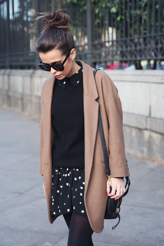 a black sweater, a star printed dress and a camel coat