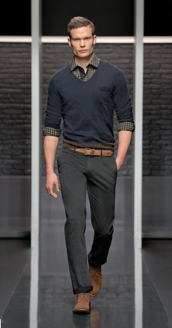 grey pants, a black sweater over a plaid shirt