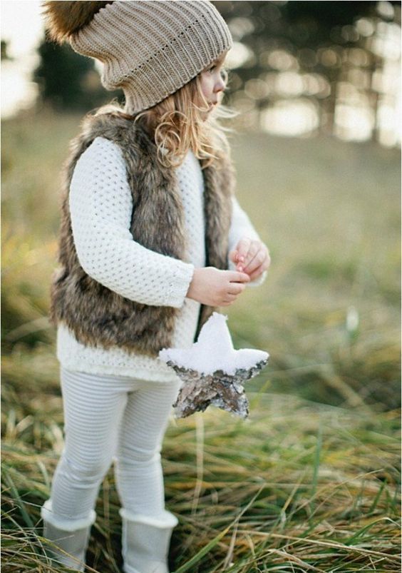 white kint sweater, leggings, a faux fur vest and a beanie