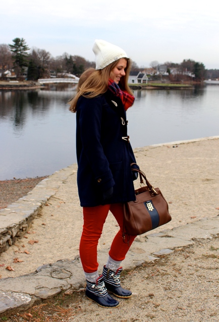 With red pants, duffle coat, plaid scarf, beanie and two color bag