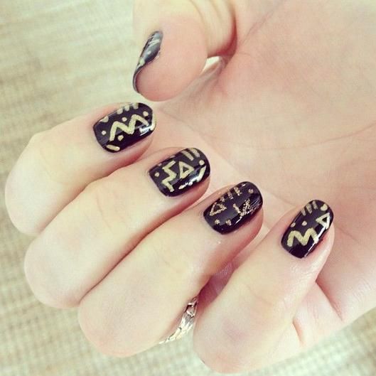 tribal nail art with gold decor on black