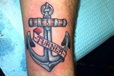 Blue, red and brown anchor tattoo on the left wrist