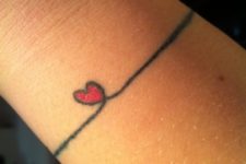 Gentle red heart tattoo on the wrist