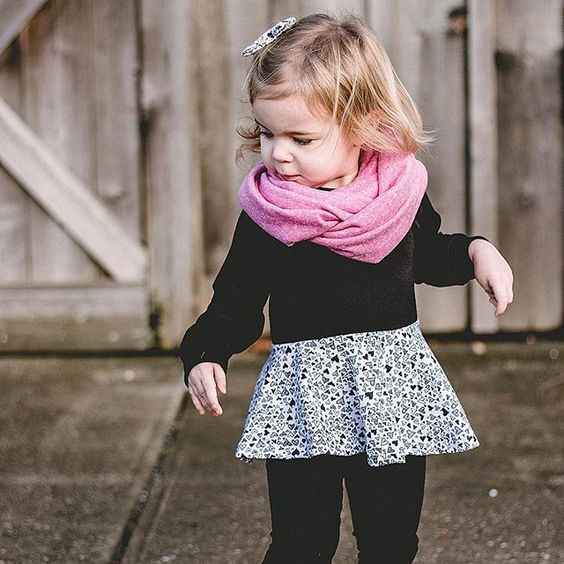 all-black look with a printed skirt and a pink scarf