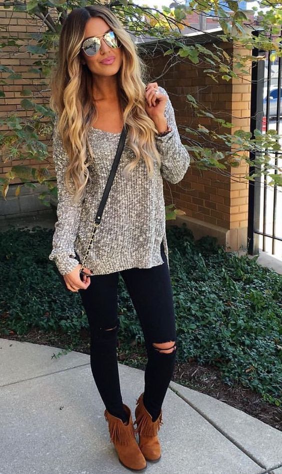 ripped black jeans, a neutral sweater and brown cowboy-styled boots