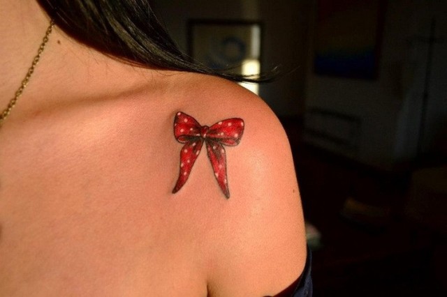 Red bow tattoo on the shoulder