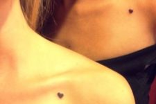 Tiny black heart tattoos on the shoulders