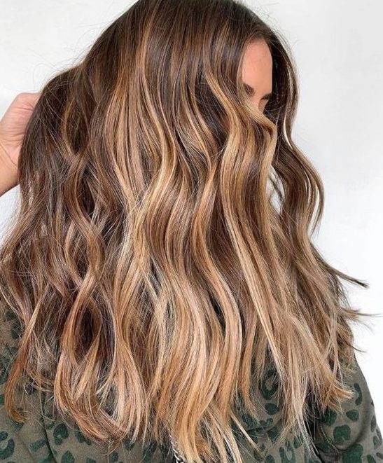 long wavy brunette hair with sunkissed balayage is a pretty idea for summer that doesn't require much maintenance