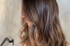 medium-length brunette hair with slight beachy highlights and a bit of wavy volume is a stylish idea for a relaxed look