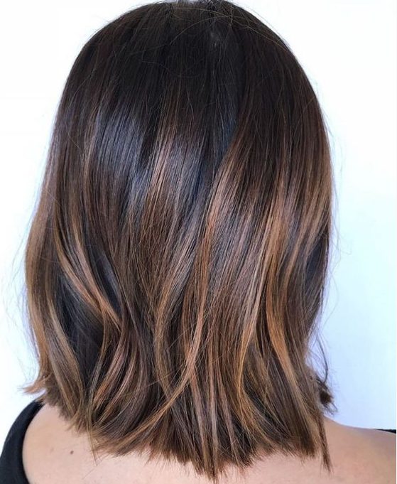 very dark brown straight long bob with delicate caramel highlights that add eye-catchiness and interest to the look
