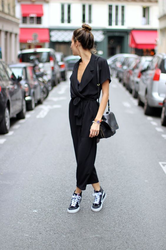 a black jumpsuit with a plunging neckline and black Vans