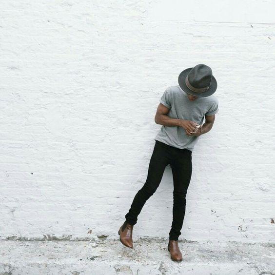 black jeans, a grey tee, brown boots and a hat