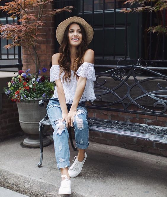 ripped blue jeans, a white lace off the shoulder top and white sneakers