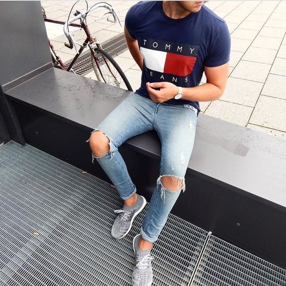 grey trainers, a printed navy t-shirt, ripped blue denim