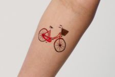 Red bicycle tattoo on the arm