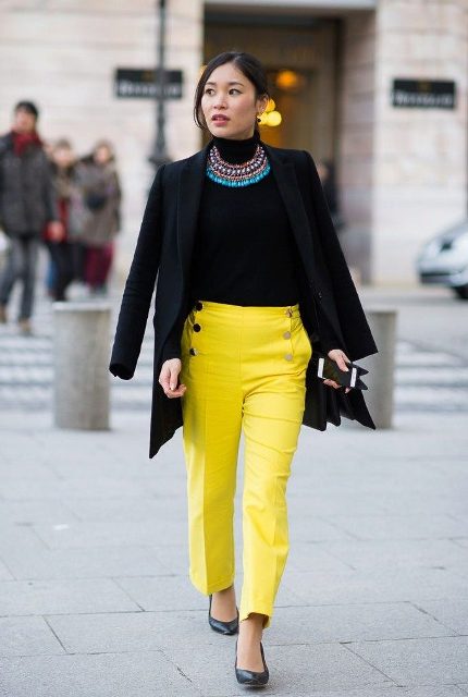With black turtleneck, black coat, classic pumps and eye-catching necklace