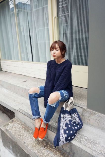With navy blue sweater, distressed jeans and tote