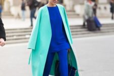 With turquoise coat, black bag and blue shoes