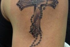 02 a cross with a rosary tattoo on an arm
