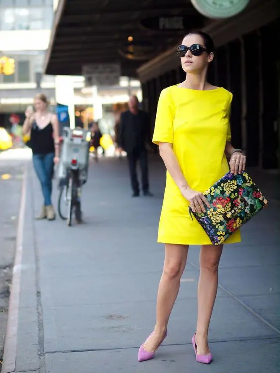 a bold yellow mini dress, pink heels and a floral clutch
